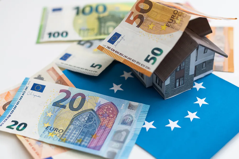 Euro banknotları ve Avrupa Birliği bayrağı üzerinde bir ev maketi