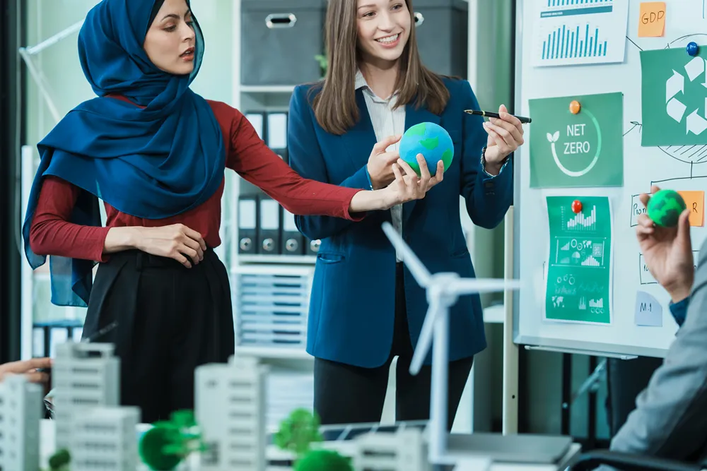 Sürdürülebilirlik toplantısında iki kadın dünya küresi ve net sıfır hedeflerini gösteren grafiklerle fikir alışverişi yapıyor
