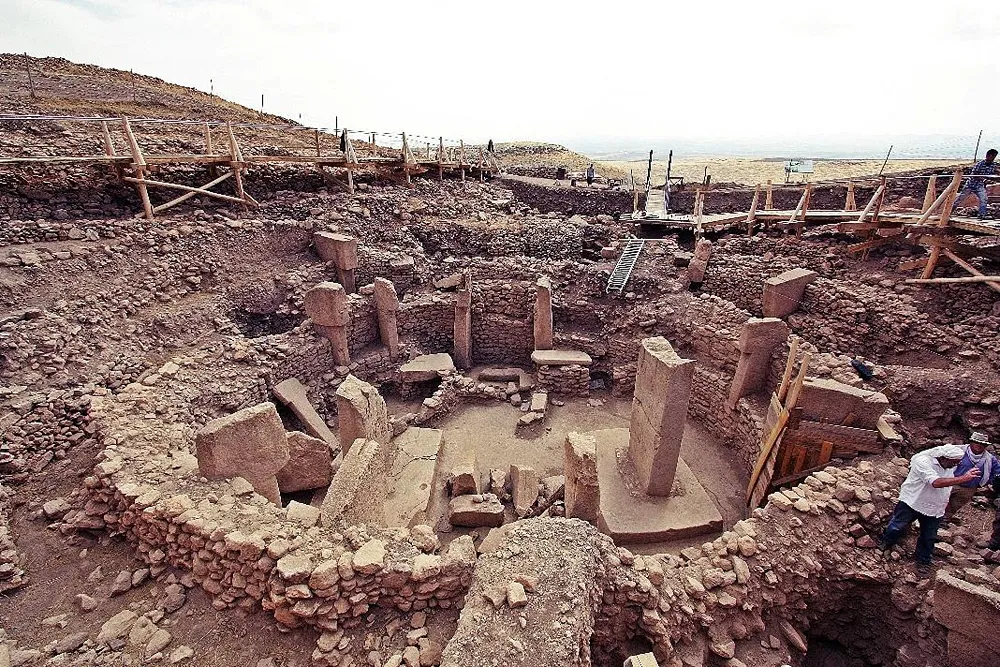 Kazı alanında taş duvarlar ve dikili taşlar arasında çalışan arkeologlar