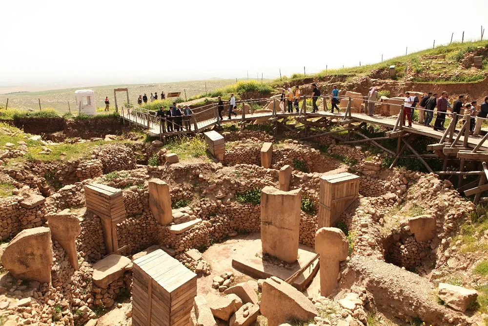 İnsanların ahşap yürüyüş yollarından gezdiği, taş duvarlar ve dikili taşların bulunduğu arkeolojik kazı alanı