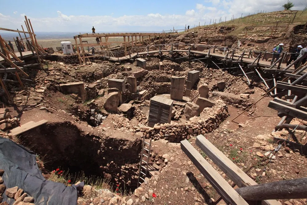 gobeklitepe (31) Arkeolojik kazı alanında taş duvar kalıntıları, ahşap yürüyüş platformları ve çalışanlar görülüyor