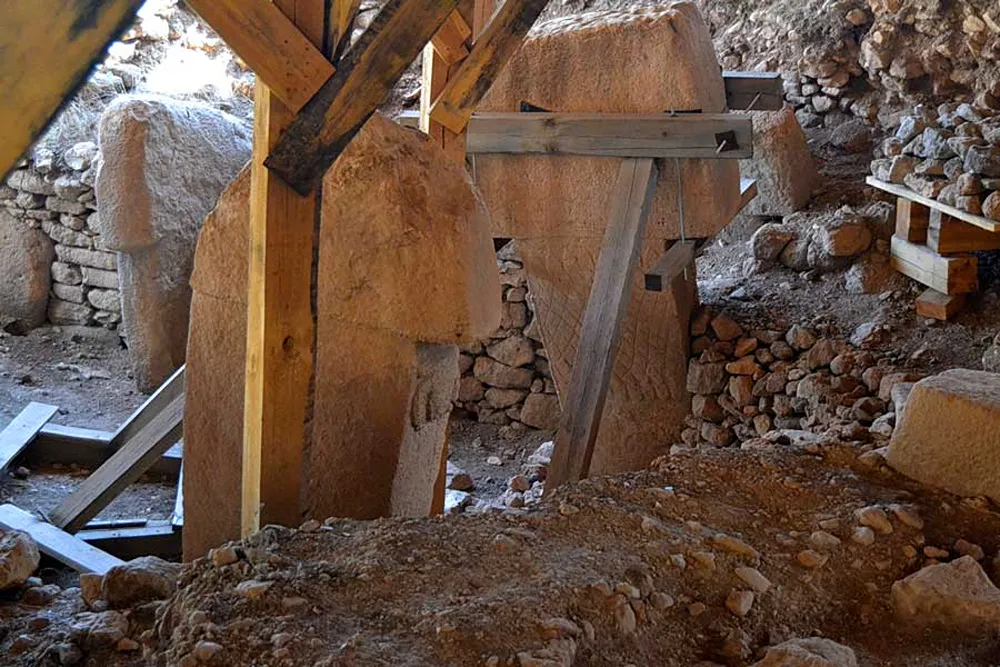 Kazı alanında ahşap desteklerle çevrelenmiş büyük taş sütunlar ve taş duvarlar