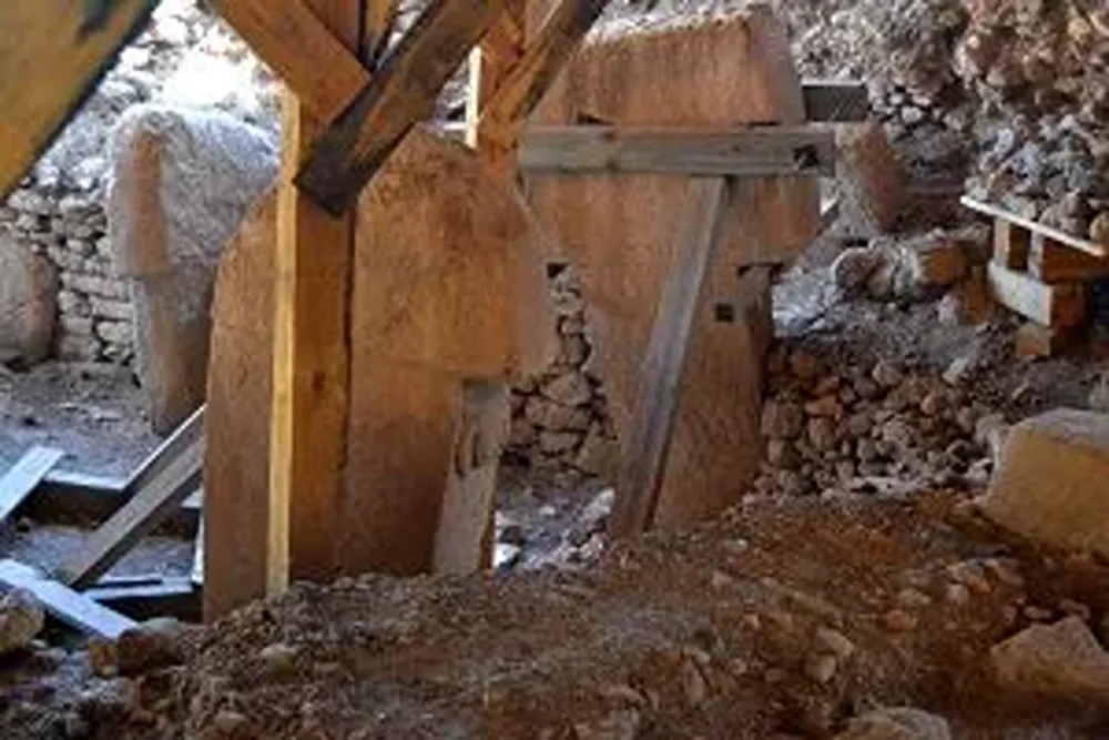 Kayalık bir alanda ahşap desteklerle çevrili, moloz ve taşlarla dolu kazı alanı