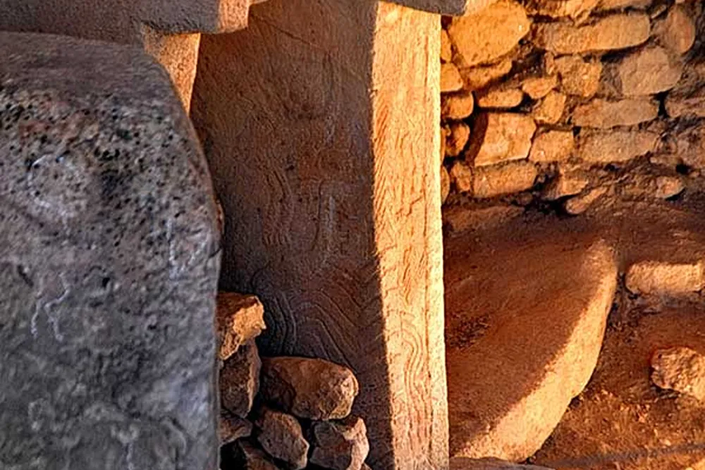 gobeklitepe (84) Güneş ışığıyla aydınlanan taş duvar ve dikey taş bloklardan oluşan eski yapı detayı