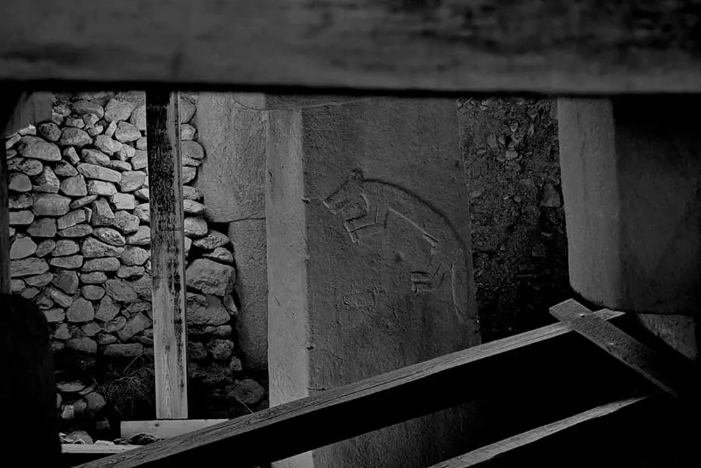 gobeklitepe (85) Taş duvarlı, sıvalı bir yapının önünde çapraz duran ahşap kirişler
