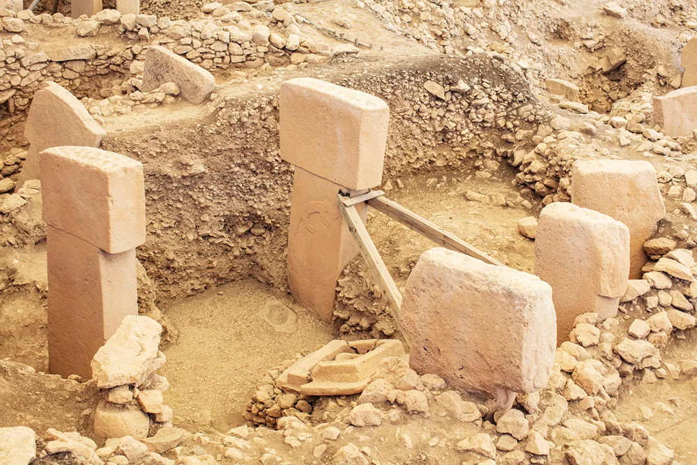 gobeklitepe (90) Arkeolojik kazı alanında, ahşap desteklerle sabitlenmiş büyük taş sütunlar ve kalıntılar