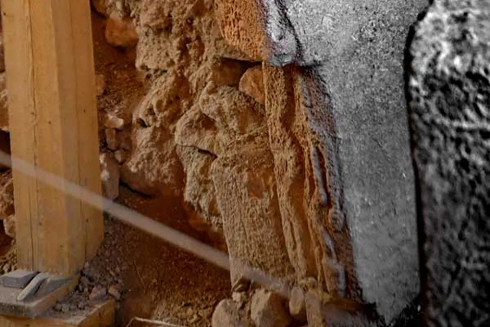 gobeklitepe (94) Ahşap dikme yanında kahverengi, lifli yapı malzemesi ve gri yüzeyin yakın planı