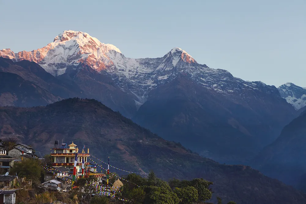 nepal-resimler (74) Ön planda renkli bayraklarla çevrili bir tapınak, arka planda karlı yüksek dağlar